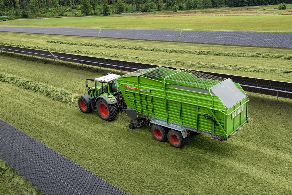 tractor driving through field between agri-pv solar panels